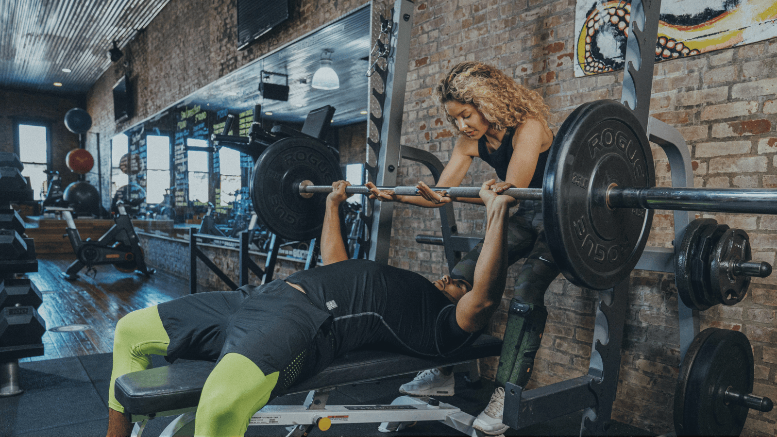Person lifting weights with a spotter in a gym setting