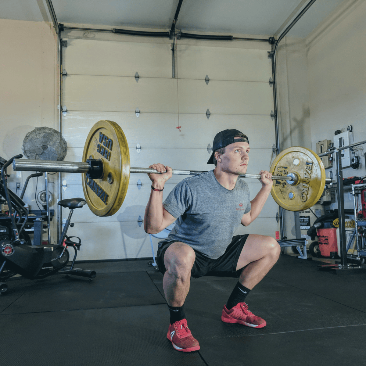 man doing barbell squat in homegym