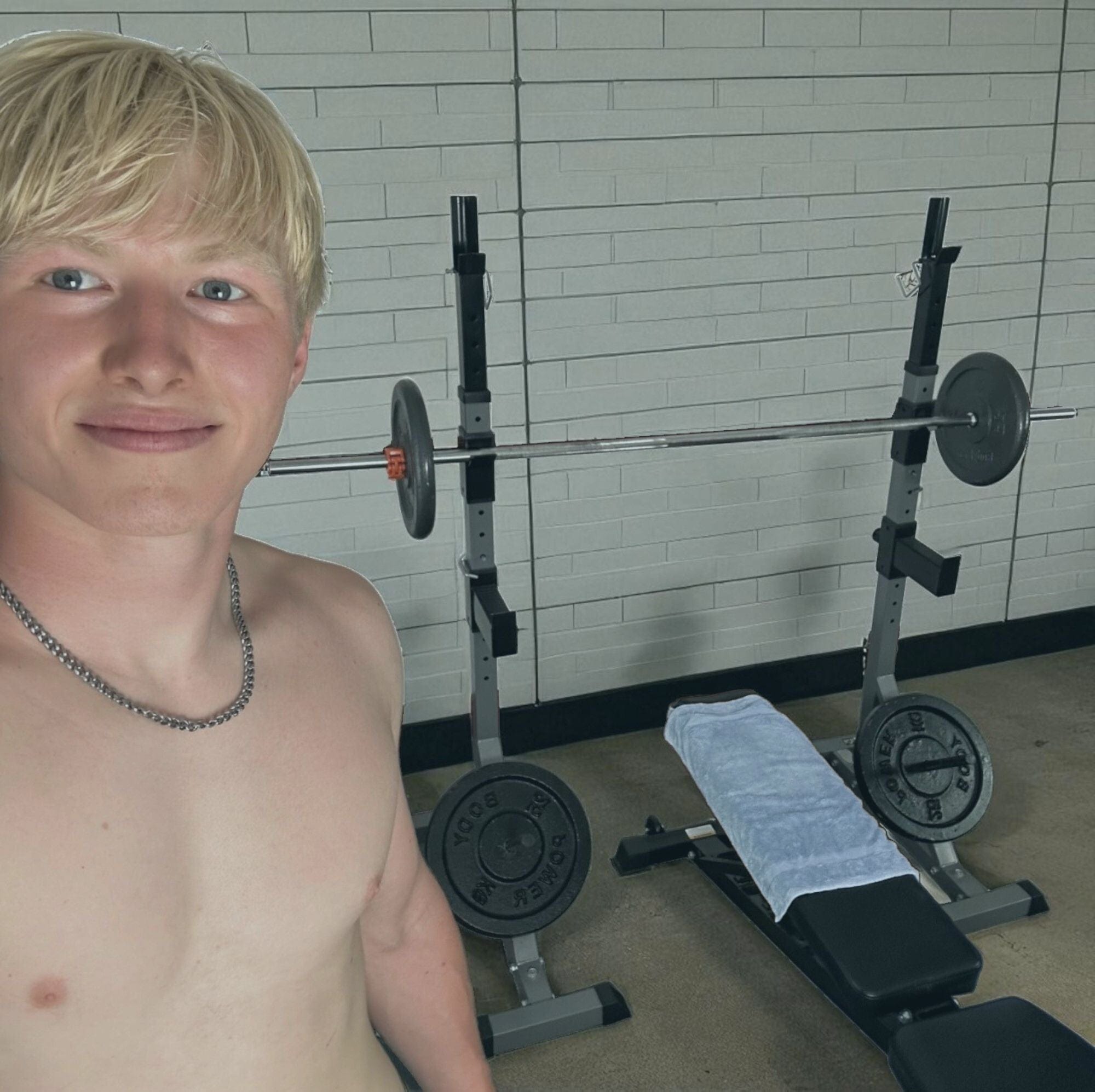 Young man standing in a gym with weightlifting equipment in the background
